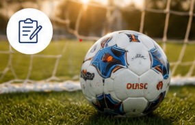Soccer ball resting on the field near a goal
